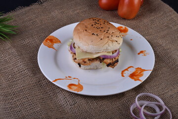 spicy chicken burger with onions pickles and lettuce on a brioche buns