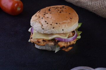 spicy chicken burger with onions pickles and lettuce on a brioche buns