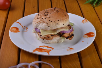 spicy chicken burger with onions pickles and lettuce on a brioche buns