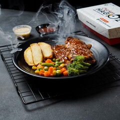 A plate of food with a box of chicken on the side