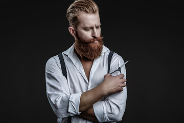 Hairstylist working in a hair salon. Barber using scissors isolated on black. Haircut from a hairstylist at a barbershop. Bearded Caucasian man hairdresser in hair salon. Classic salon