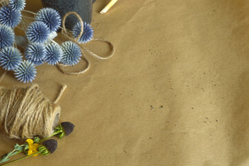 gardening themed, planting table, flat lay, string, black and blue flowers, blue globe thistle, beige wrapping paper covered table, top view, copy space,