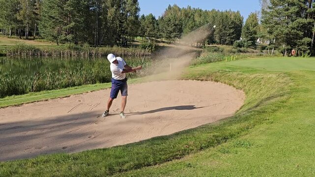 Golfer practices short game techniques in a sand trap at a lush green golf course
