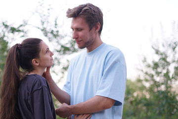 Obraz premium A man and woman are hugging in a park, smiling at each other. They are happy and playful