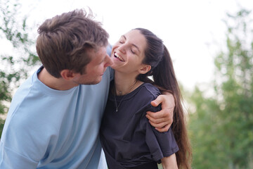 Obraz premium A man and woman are hugging in a park, smiling at each other. They are happy and playful