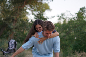 couple enjoys a romantic moment in a lush forest as the man lifts the woman off the ground, her arms wrapped around his neck, and her head tilted back in laughter