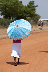 Woman in South Sudan walking with an umbrella.