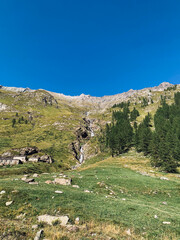 Mountain landscape with green meadows and flowing waterfall. Natural background.