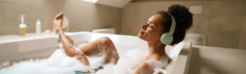 Woman leisurely bathing in bathtub with headphones on