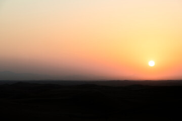The desert at sunrise, showcasing a bright yellow-orange sky with plenty of copy space, making it a perfect background for text or creative work