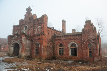 Fototapeta premium Abandoned brick house with a decayed wall and broken window in a misty area