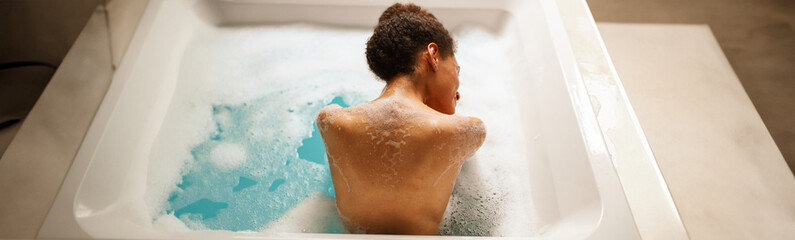 Woman happily bathing in waterfilled bathtub for leisure