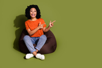 Full body portrait of nice young woman direct fingers empty space wear t-shirt isolated on khaki color background © deagreez
