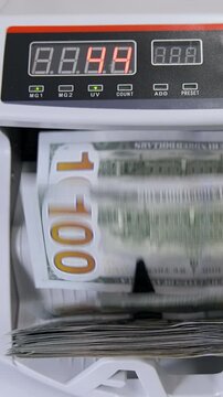 Automatic money counting in the machine. Electronic money machine is counting the dollar banknotes. Front view. Close-up. Vertical video