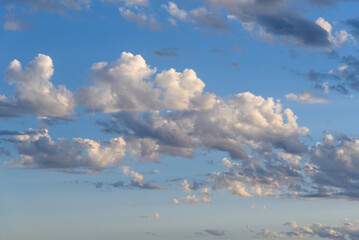 Beautiful white puffy clouds against blue sky during dramatic sunset