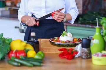 chefs hands with a knife preparing food from fresh vegetables