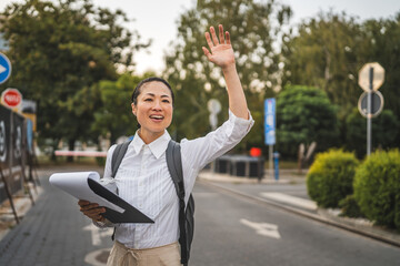 Japanese mature woman hailing taxi with clipboard on street in city