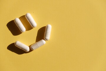 The pills are laid out as a smiley face on a yellow background. Medications. Concept: successful treatment, recovery. Vitamins. 