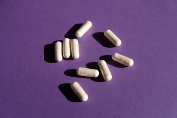 Scattered pills on a purple background. Medications. Concept: successful treatment, recovery....