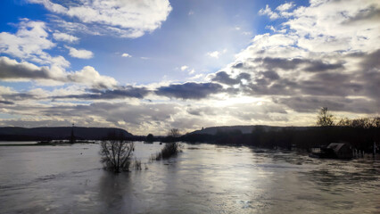 A serene landscape of a flooded river under dramatic skies, reflecting sunlight and nature's beauty. Ideal for environmental themes or landscapes.