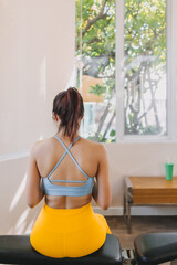 Lazy asian woman in Yellow Blue fitness outfit using mobile in the gym.