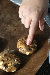 A woman is making healthy cookies. With nuts and chocolate. She is placing the cookie dough portions on the baking sheet.