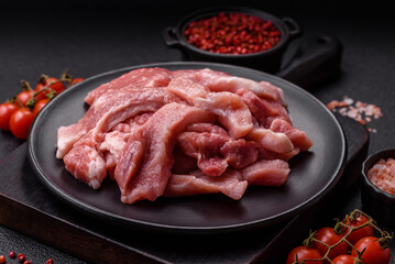 A pieces of raw fresh pork on a wooden cutting board with spices and herbs