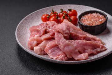 A pieces of raw fresh pork on a wooden cutting board with spices and herbs