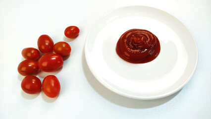 Cherry tomatoes and  ketchup in a small dish on the white background.
