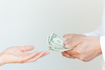 The man is counting American money and the woman reaches out her hand to take the money from him