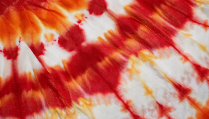 A tie-dye pattern featuring red, orange, and white on fabric background, created with a dip-dye technique.