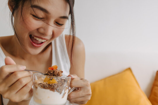 Enjoy face of Asian woman eating dessert made of yogurt. Happy healthy diet.