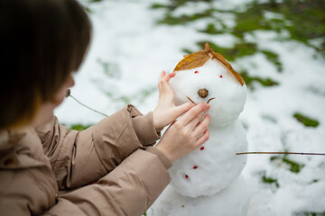 Adorable young girl building a snowman in the backyard. Cute child playing in a snow. Winter...