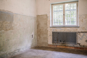 Munich, Germany - September 13, 2024 - An empty, dilapidated room with peeling walls, a metal...