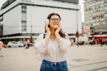 Young caucasian woman listening to music or audio book in the city