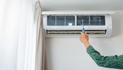 A hand cleaning a dirty air conditioner unit with a brush.  The unit is mounted on a wall.
