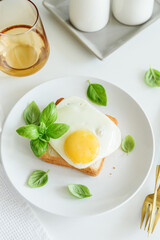 Croque madam sandwich with cheese and egg on white wooden table.