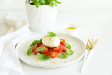 Salad Caprese with tomato, cherry, mozzarella and basil leaves on white wooden table