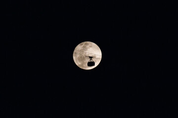 silhouette of the Sugarloaf Mountain cable car with a beautiful full moon in the background in Rio de Janeiro.