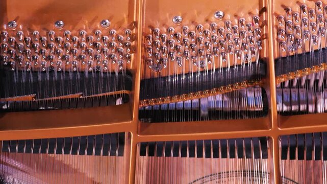 Close-up of the inside of a piano with strings, pegs and hammers. Mechanism of the piano during playing. View from above