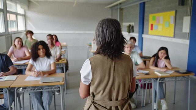 College students listen to a passionate, mature female teacher giving a motivational speech during a high school lecture