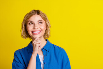 Portrait of pretty young lady look empty space wear blue shirt isolated on yellow color background