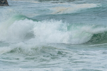 Wave of the green and blue Atlantic Ocean at the edge of a beach in the Iroise Sea.