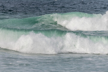 Wave of the green and blue Atlantic Ocean at the edge of a beach in the Iroise Sea.