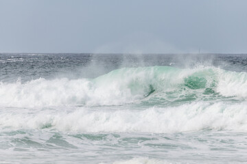 Wave of the green and blue Atlantic Ocean at the edge of a beach in the Iroise Sea.