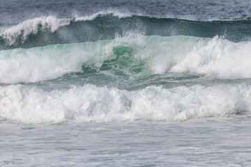 Wave of the green and blue Atlantic Ocean at the edge of a beach in the Iroise Sea.