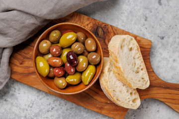 An assortment of various olives presented in a bowl, showcasing different colors, textures, and...