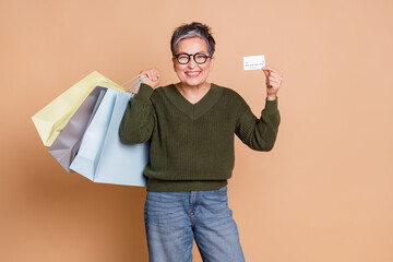 Photo of lovely cheerful adorable senior woman wear green stylish clothes hold packages bank card...