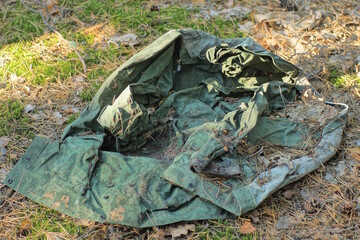 one piece of old green dirty cloth clothes lies on the ground on a summer street
