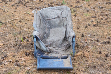 one old blue gray broken baby carriage lies on the ground on a summer street